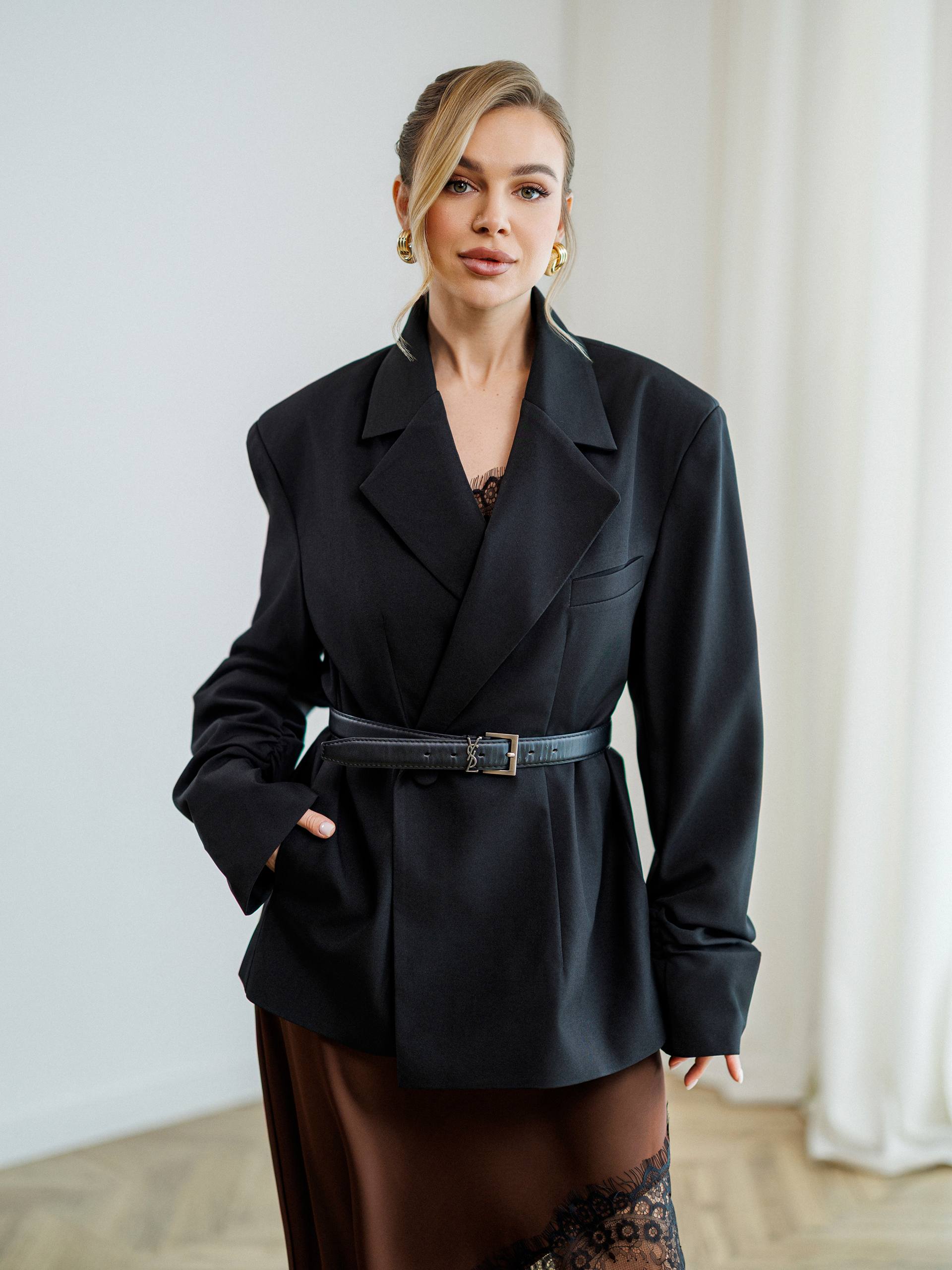 Woman wearing a black coat with a belt in an indoor setting