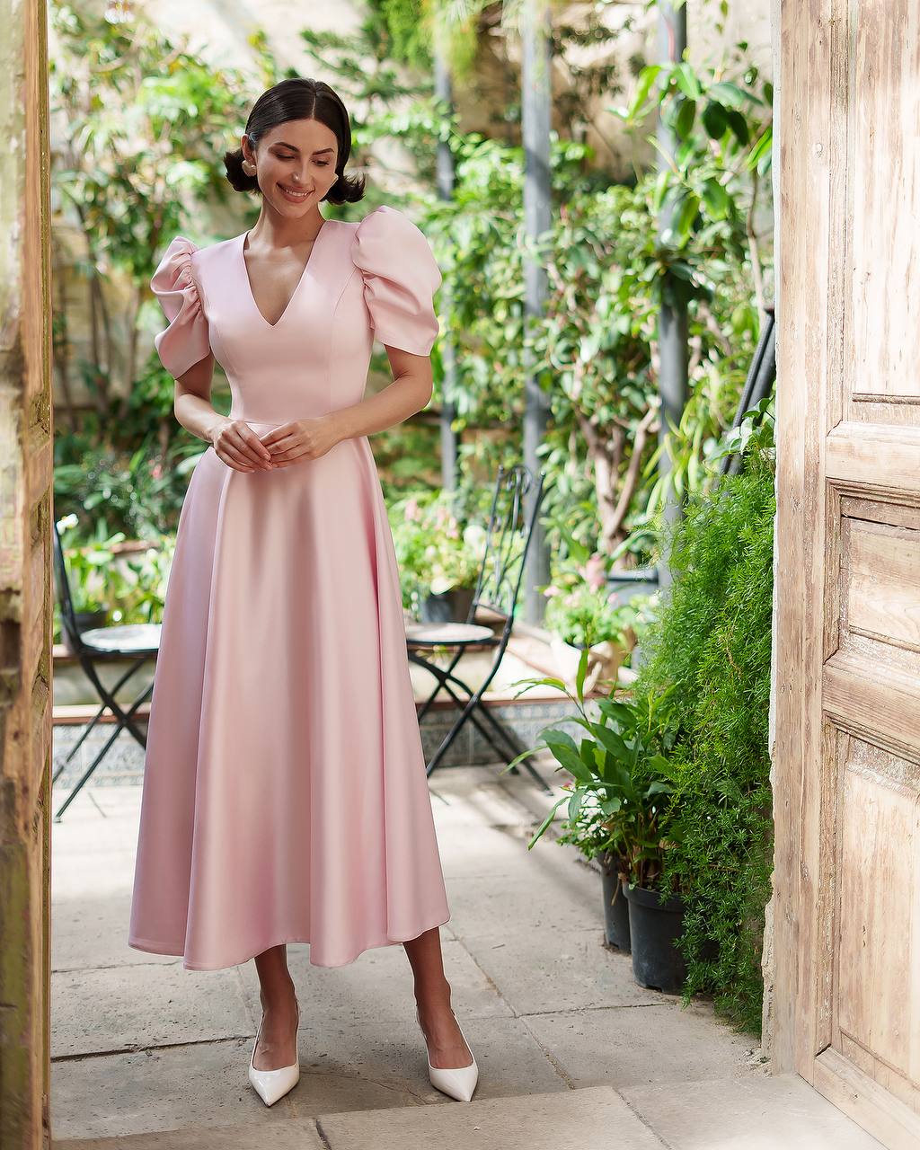Woman in a pink dress standing in a garden setting