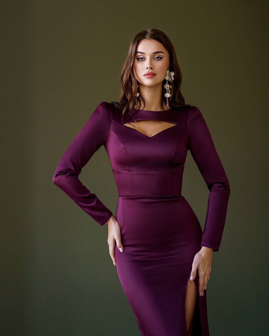 Woman wearing a purple dress with long sleeves against a green background