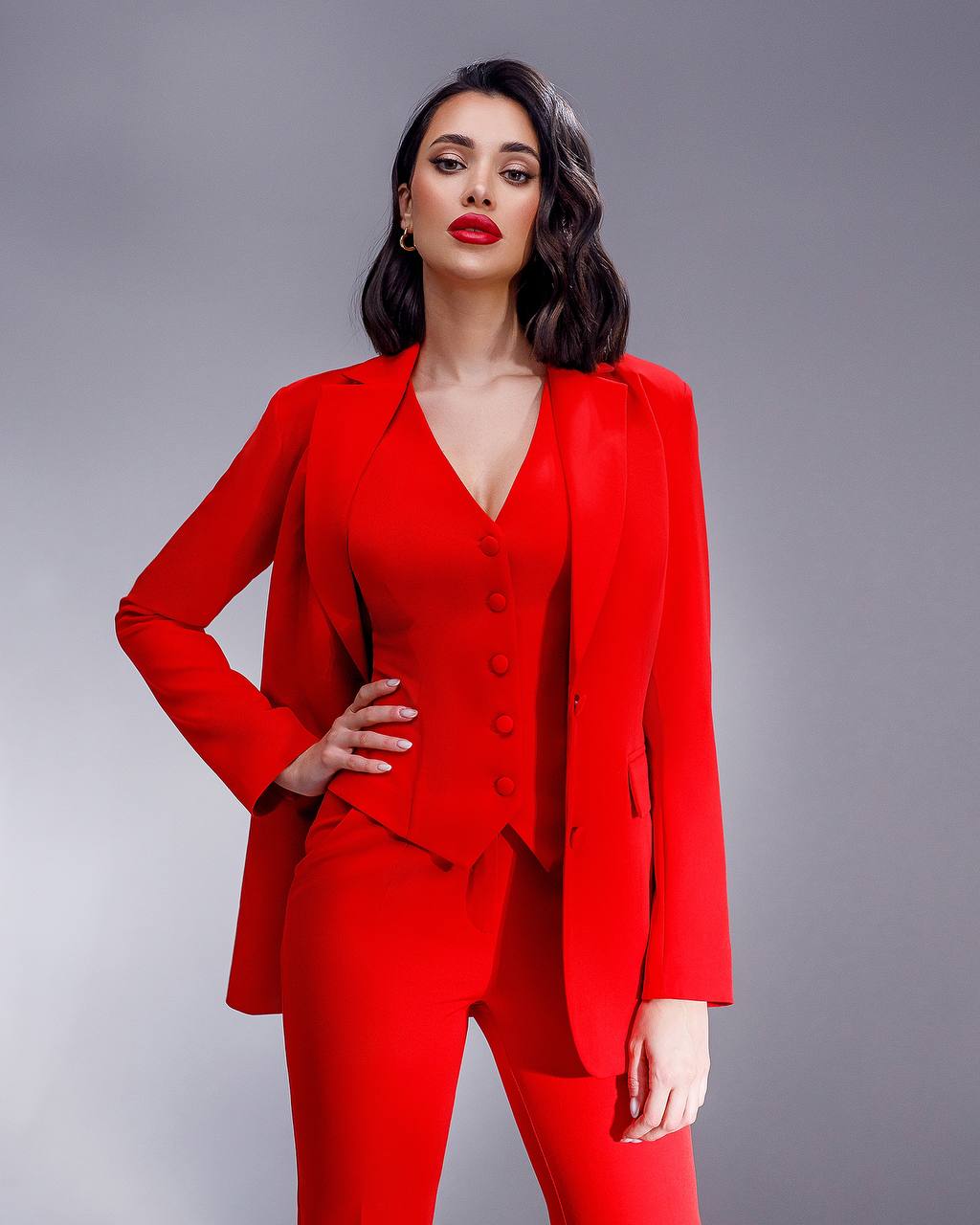 Woman wearing a red suit against a gray background