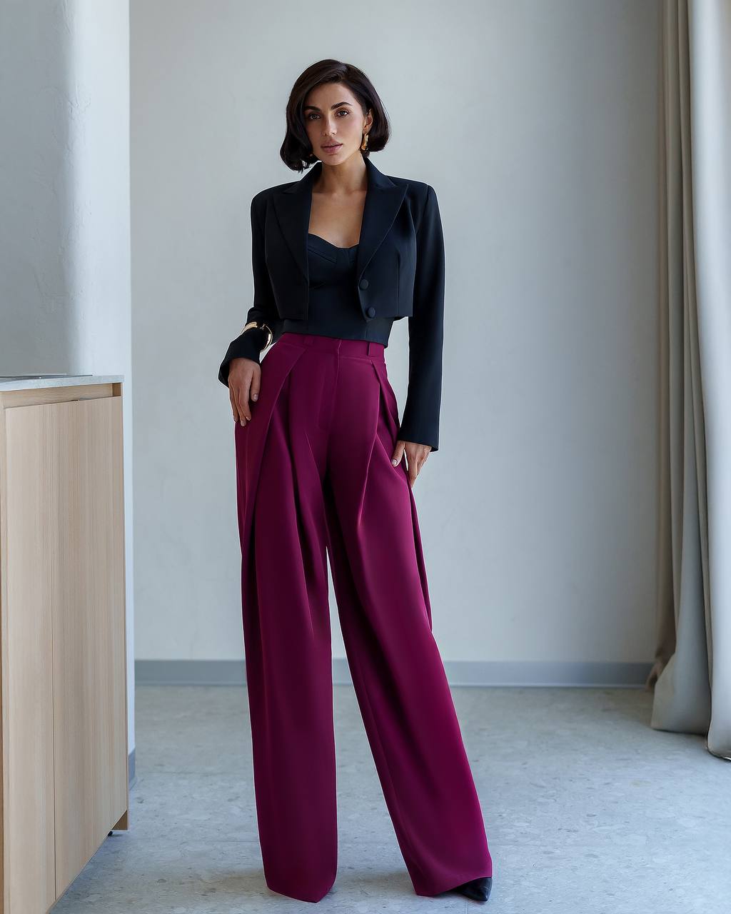 Woman wearing a black blazer and magenta pants in an indoor setting
