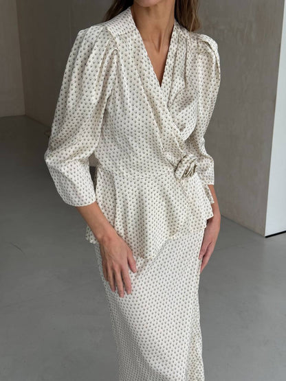 Woman wearing a white dress with black polka dots in a minimalistic setting
