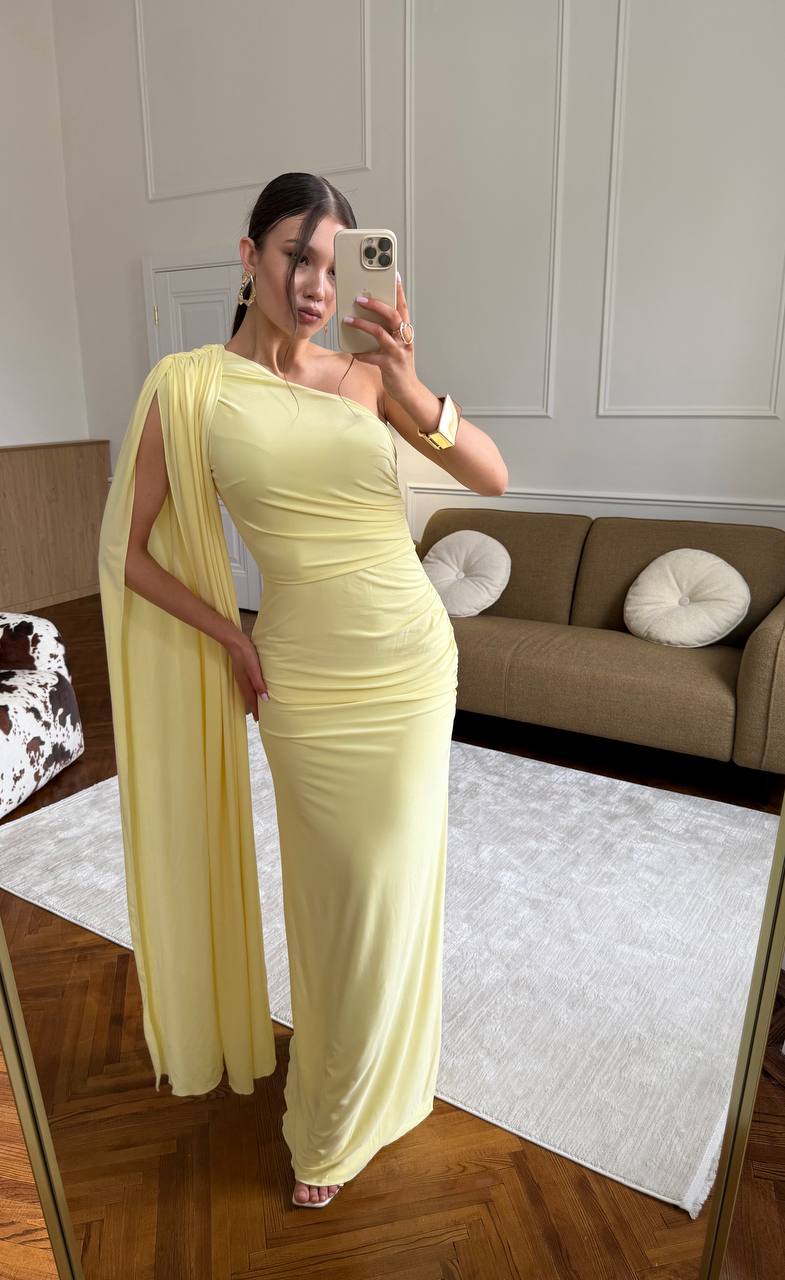 Woman in a yellow dress taking a mirror selfie in a living room.