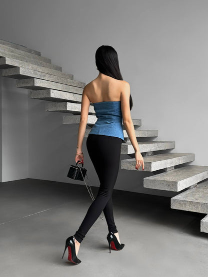 Woman in a blue top and black pants walking up a set of concrete stairs.