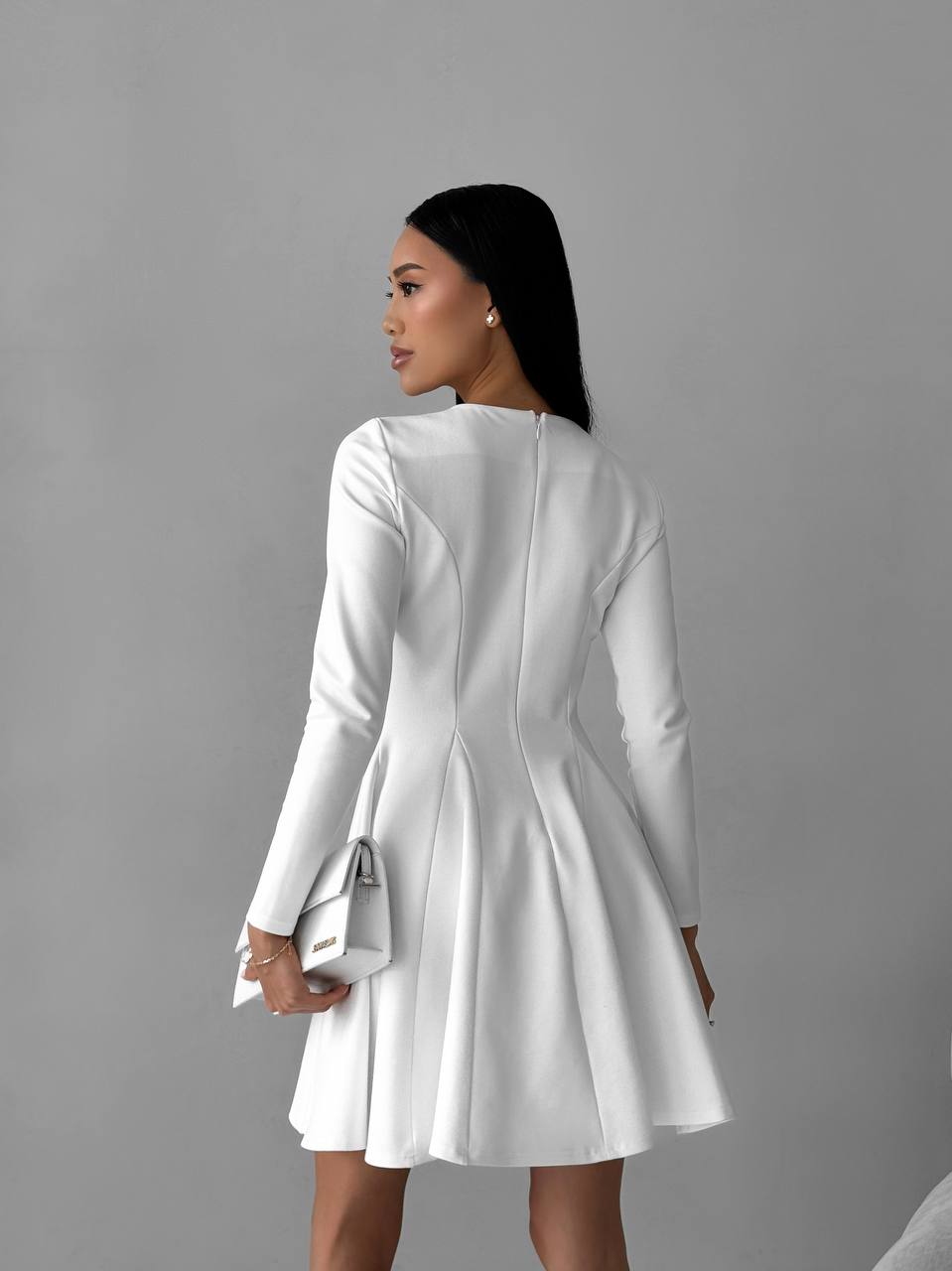 Woman wearing a white dress against a gray background