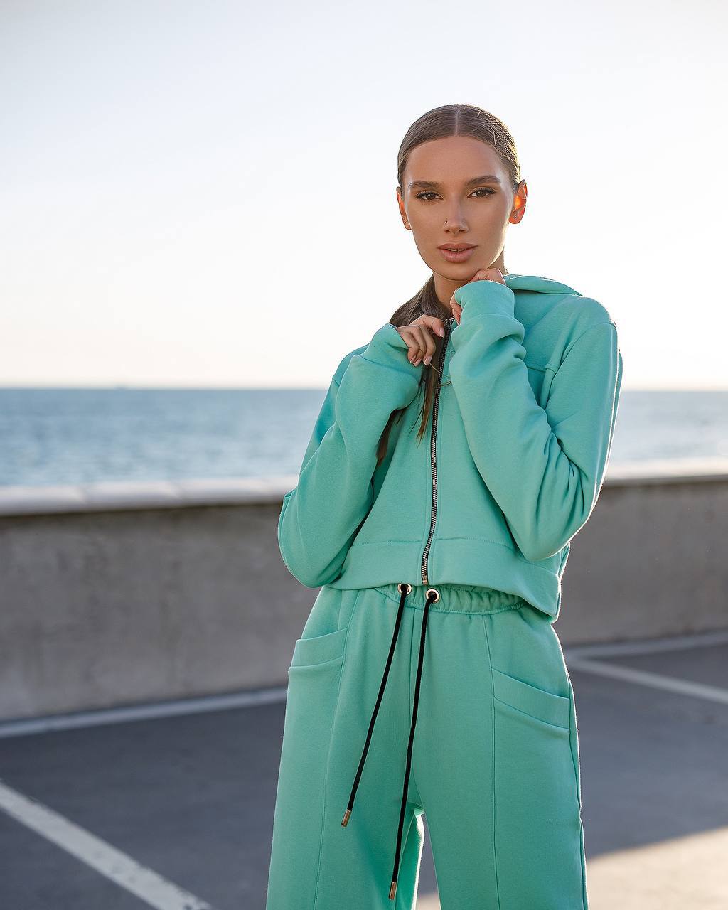 Woman wearing a teal tracksuit standing on a road with a blurred background