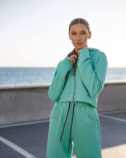 Woman wearing a teal tracksuit standing on a road with a blurred background