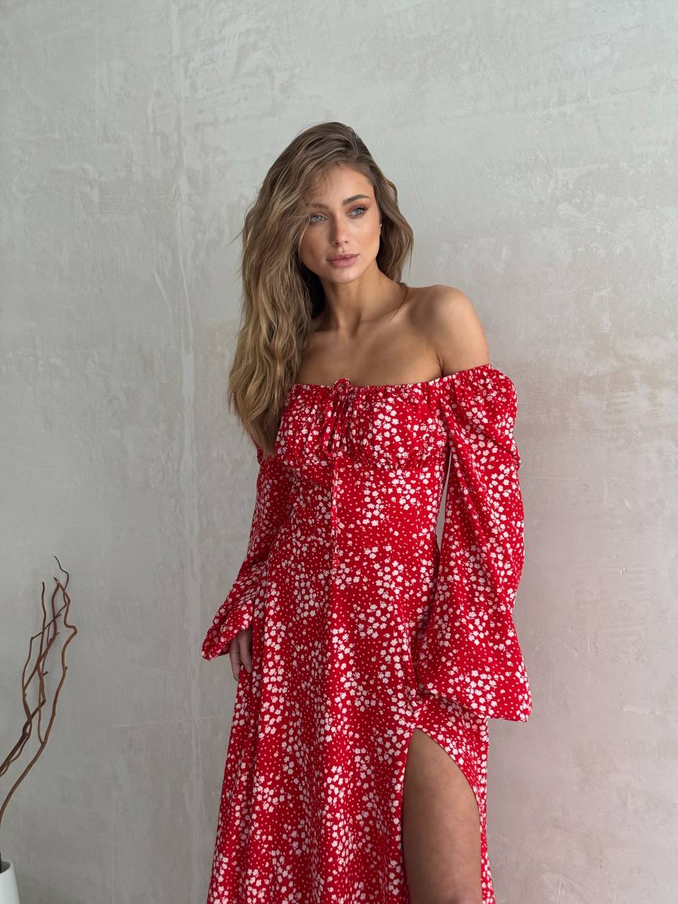 Woman wearing a red floral off-shoulder dress against a plain background