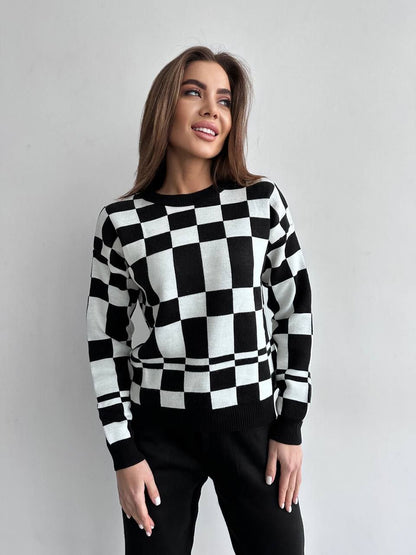 Woman wearing a black and white checkered sweater against a plain background