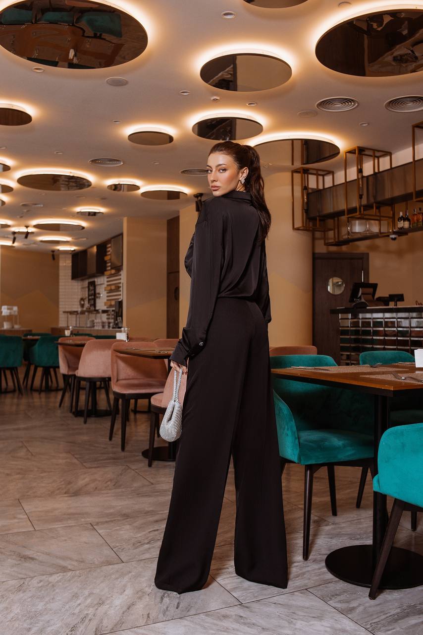 Woman in a black outfit standing in a modern restaurant with stylish interior design.