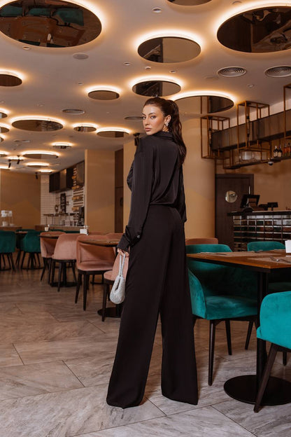 Woman in a black outfit standing in a modern restaurant with stylish interior design.