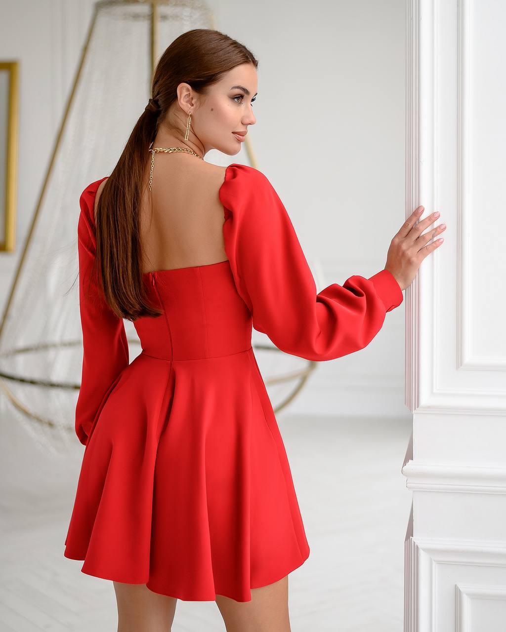 Woman wearing a red dress with a backless design in an elegant interior setting.