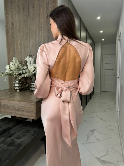 Woman in a pink satin dress standing in a modern interior setting.