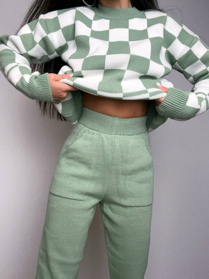 Person wearing a green and white checkered sweater and matching pants against a gray background