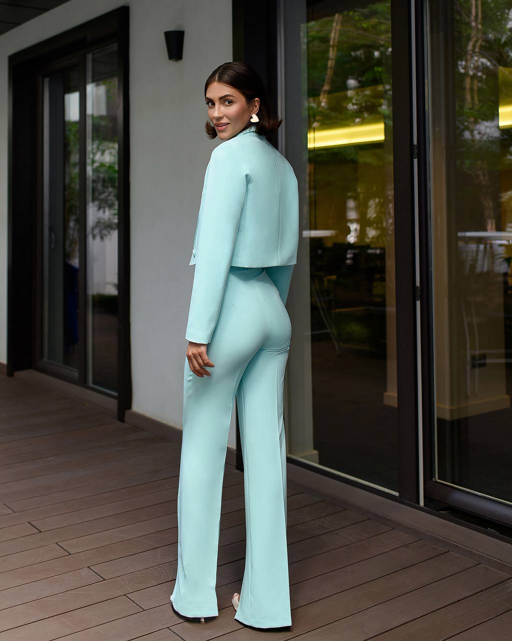 Woman in a light blue suit standing on a wooden deck.