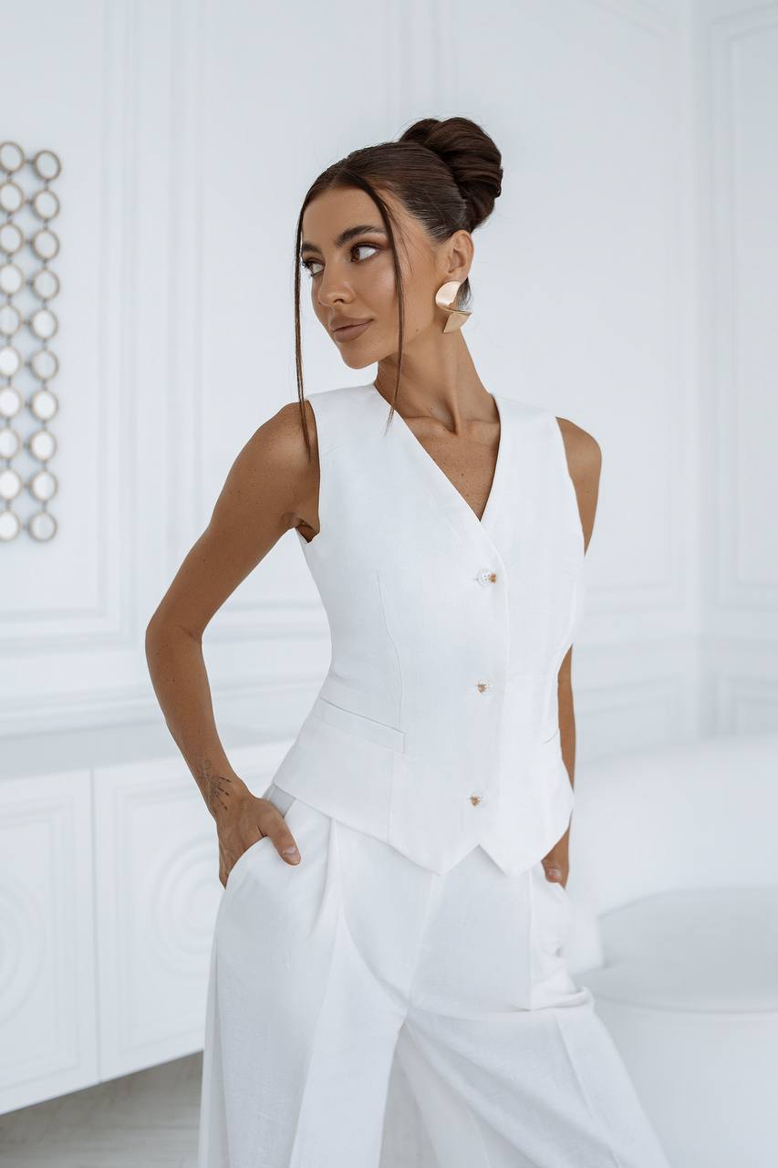 Woman wearing a white sleeveless top and pants in a minimalistic setting