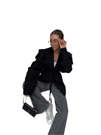 Person wearing a black coat and gray pants sitting on a white background