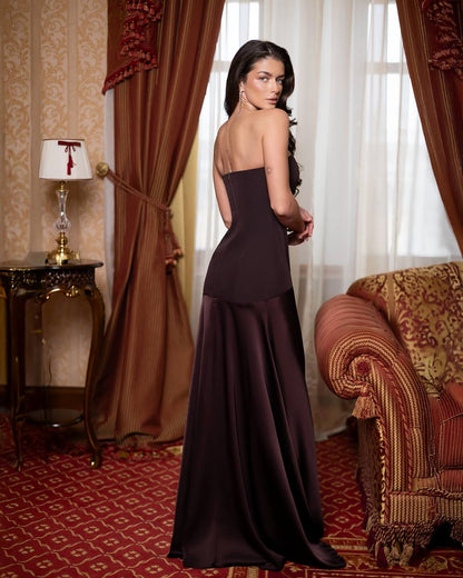 Woman in a dark purple evening gown standing in an opulent room with red and gold decor.