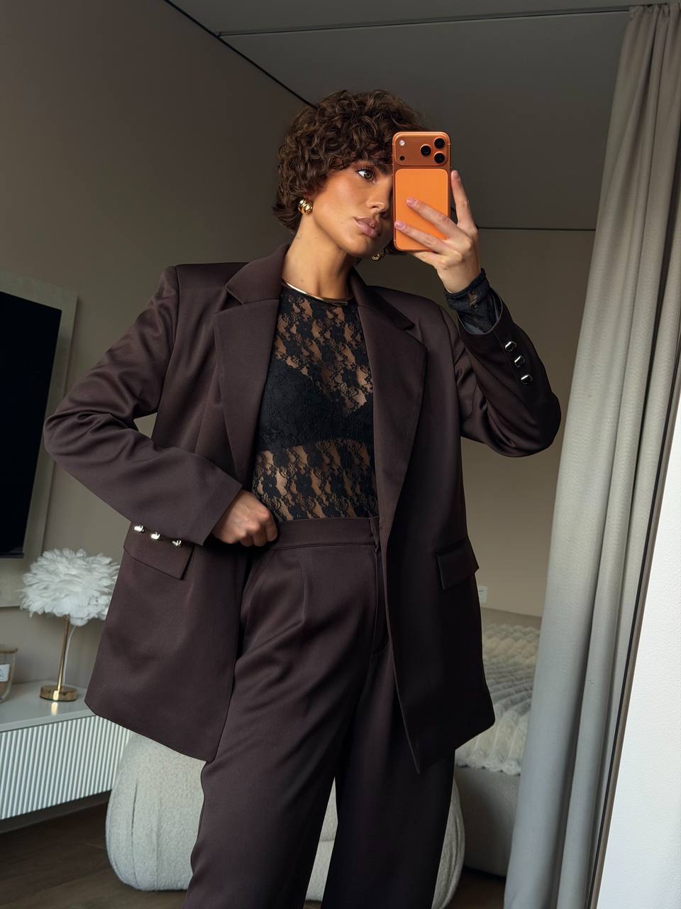 Person taking a mirror selfie wearing a brown suit in a room.