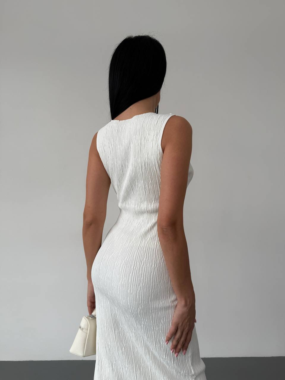 Person wearing a white sleeveless dress against a plain background