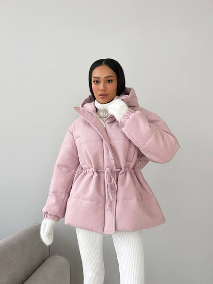 Person wearing a pink puffer coat against a plain background