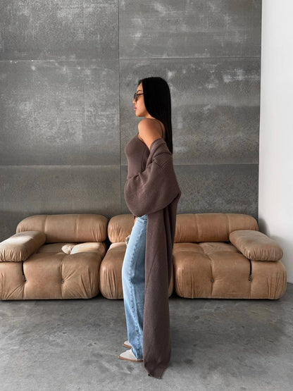 Woman standing in a modern living room with a brown sofa and gray wall.