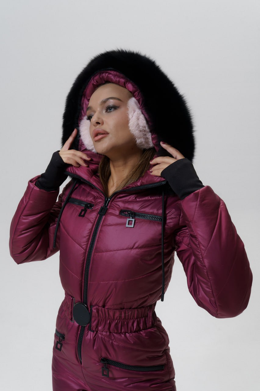 Person wearing a maroon winter suit with a fur-lined hood on a light gray background