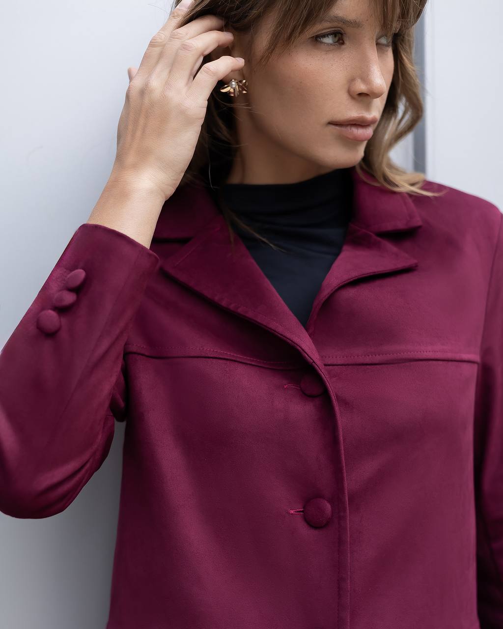 Woman wearing a burgundy coat against a light background