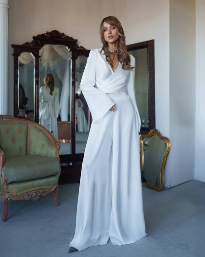 Woman in a white dress standing in a room with vintage furniture.