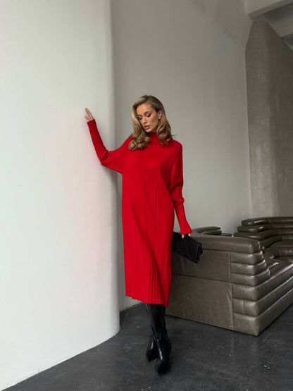 Woman in a red dress standing against a white wall with a modern interior background.
