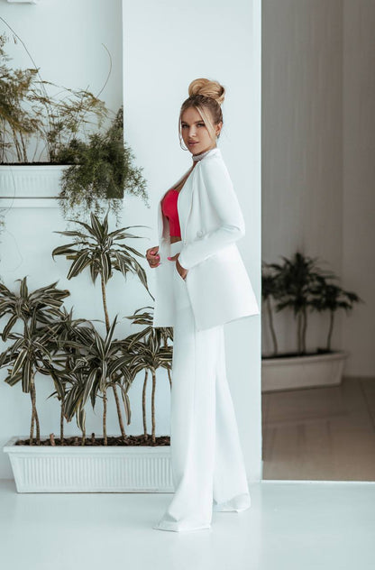 Woman in a white outfit standing in a room with plants