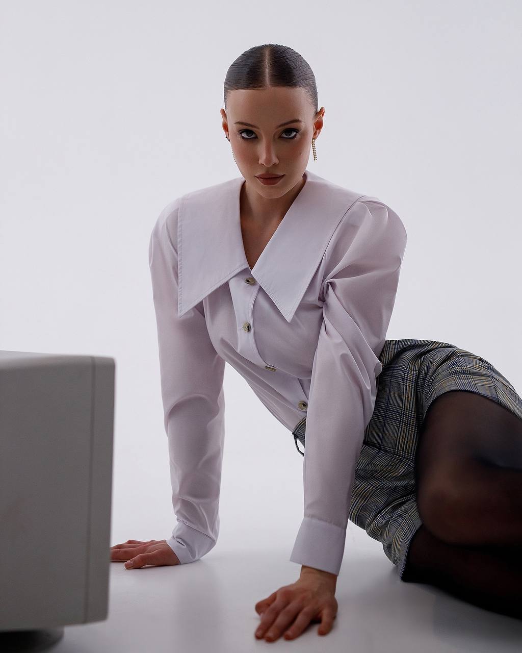 Person wearing a light purple shirt and gray shorts on a white background