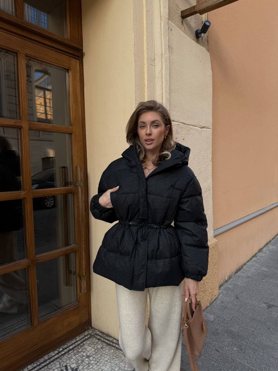Woman wearing a black puffer jacket standing on a street.