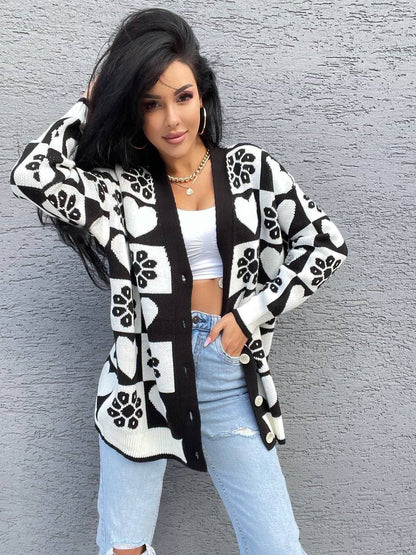 Woman wearing a black and white patterned cardigan against a gray wall