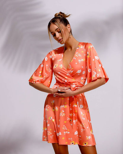 Woman wearing a coral floral dress against a plain background