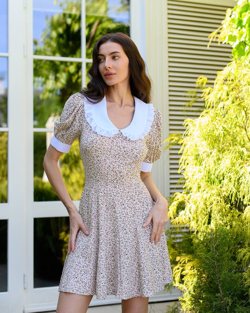 Woman wearing a floral dress with a white collar in an outdoor setting
