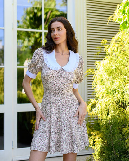 Woman wearing a floral dress with a white collar in an outdoor setting