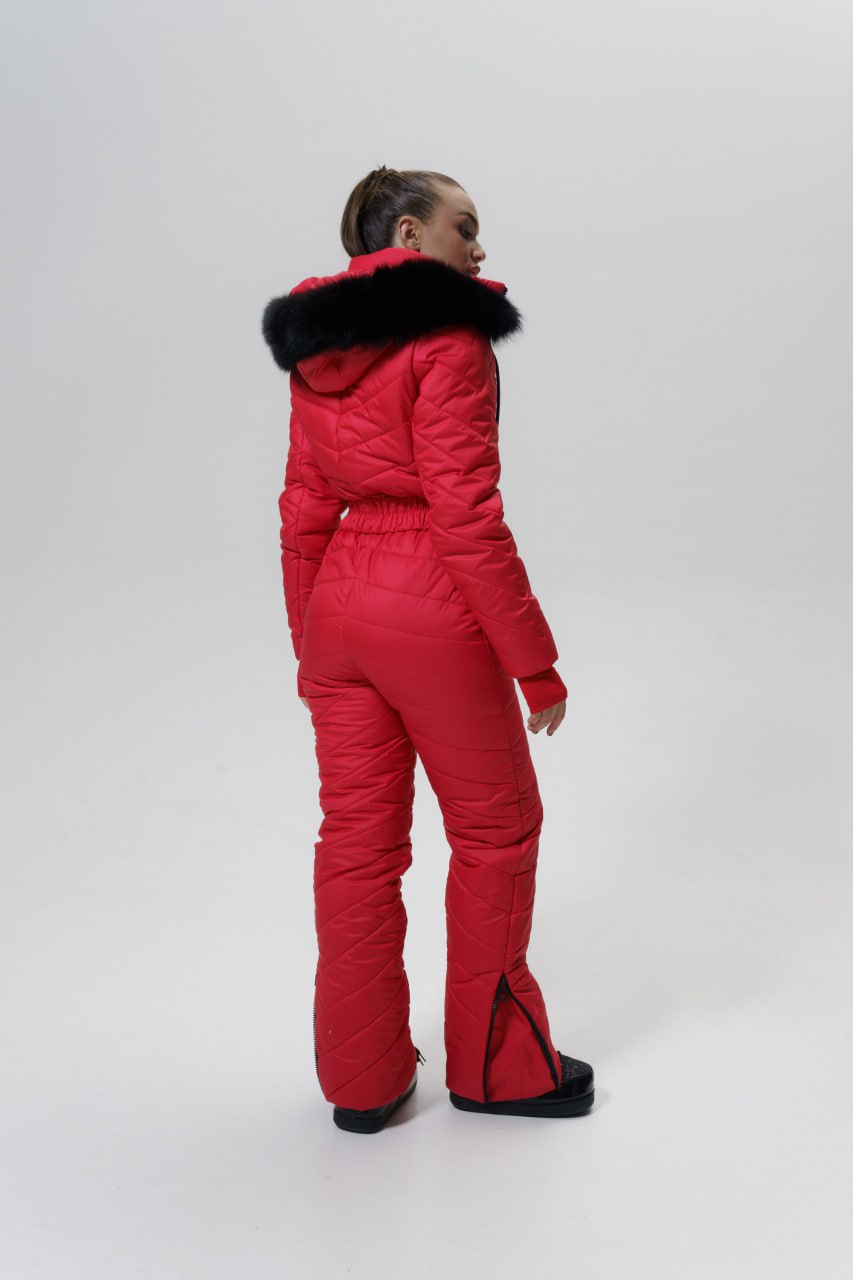 Person wearing a red snowsuit with black fur trim on a white background