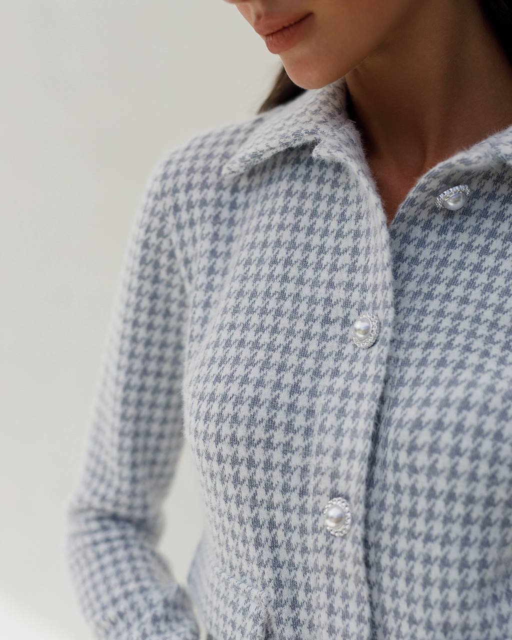 Close-up of a person wearing a blue and white checkered shirt with a plain background