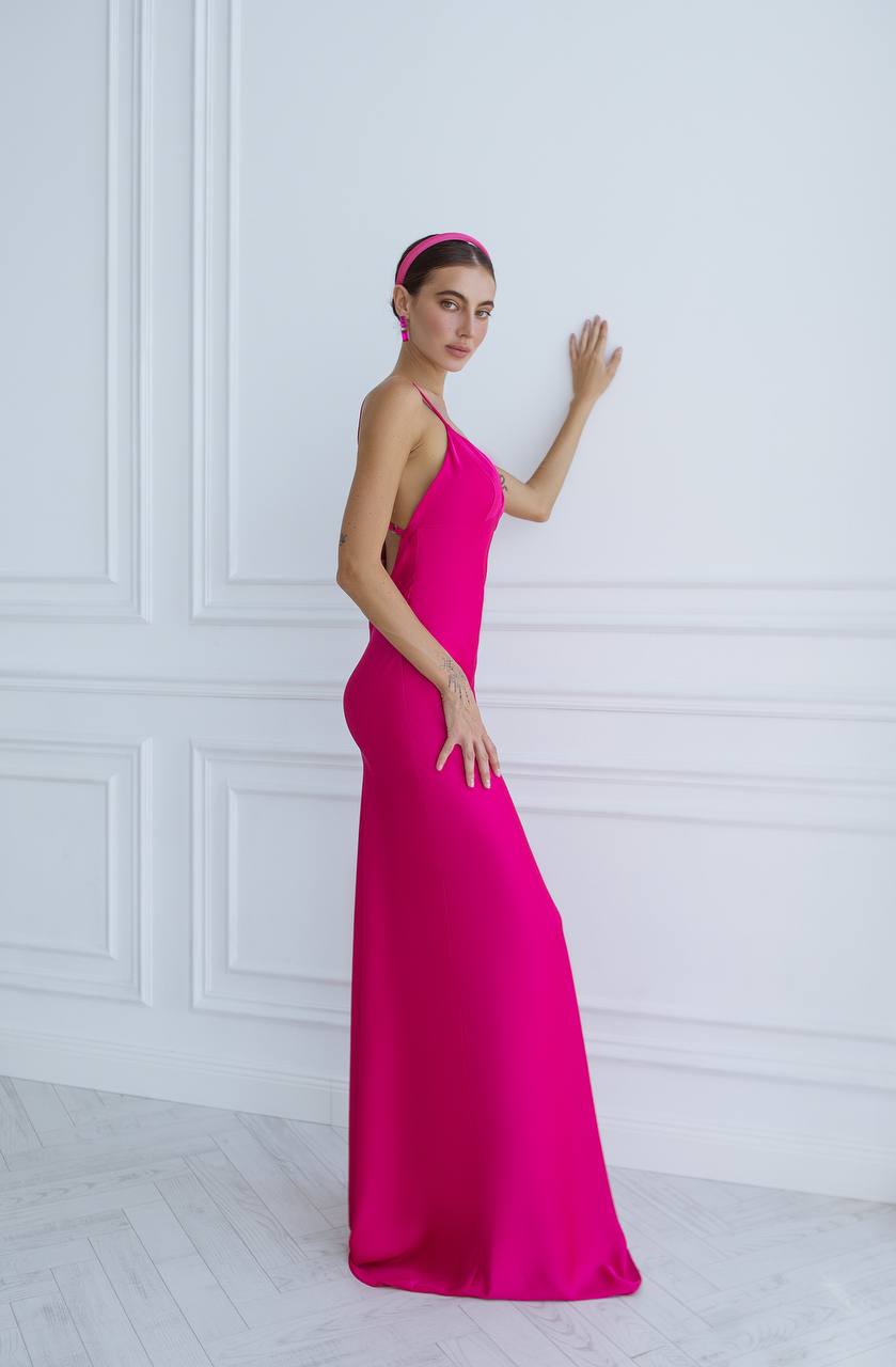 Woman wearing a bright pink evening gown against a white wall.