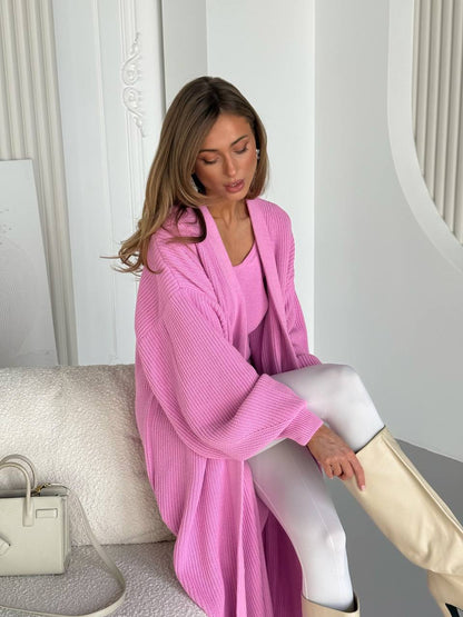 Woman wearing a pink robe sitting on a white couch in a minimalistic room.