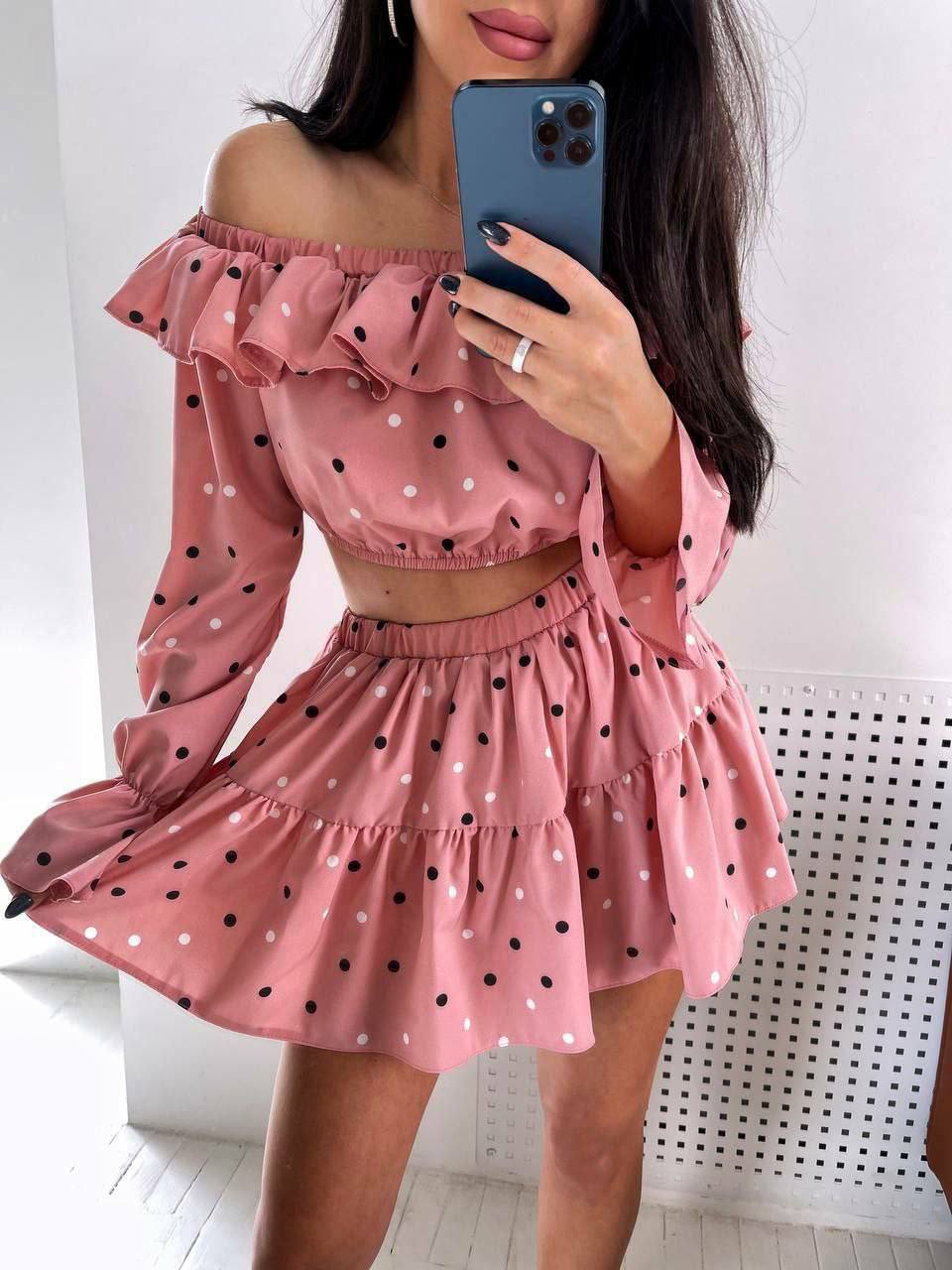Person wearing a pink polka dot dress taking a mirror selfie.