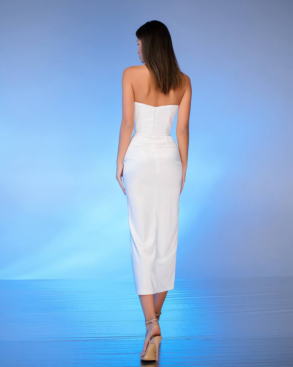 Woman wearing a white strapless dress against a blue gradient background