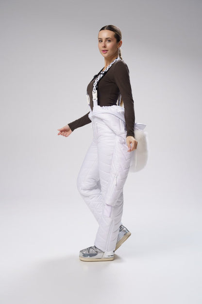Woman wearing a brown top and white pants on a gray background