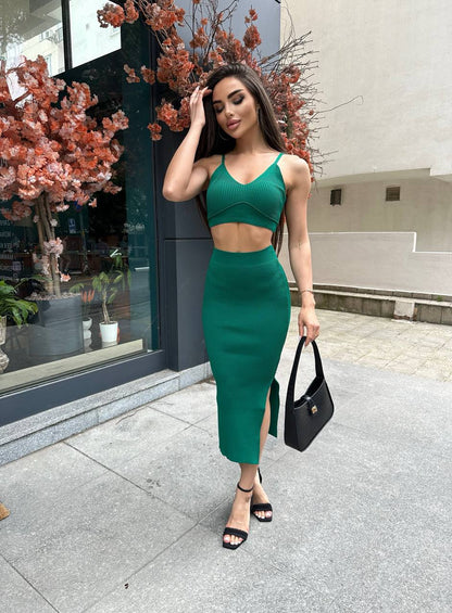 Woman in a green outfit standing on a street with decorative plants.