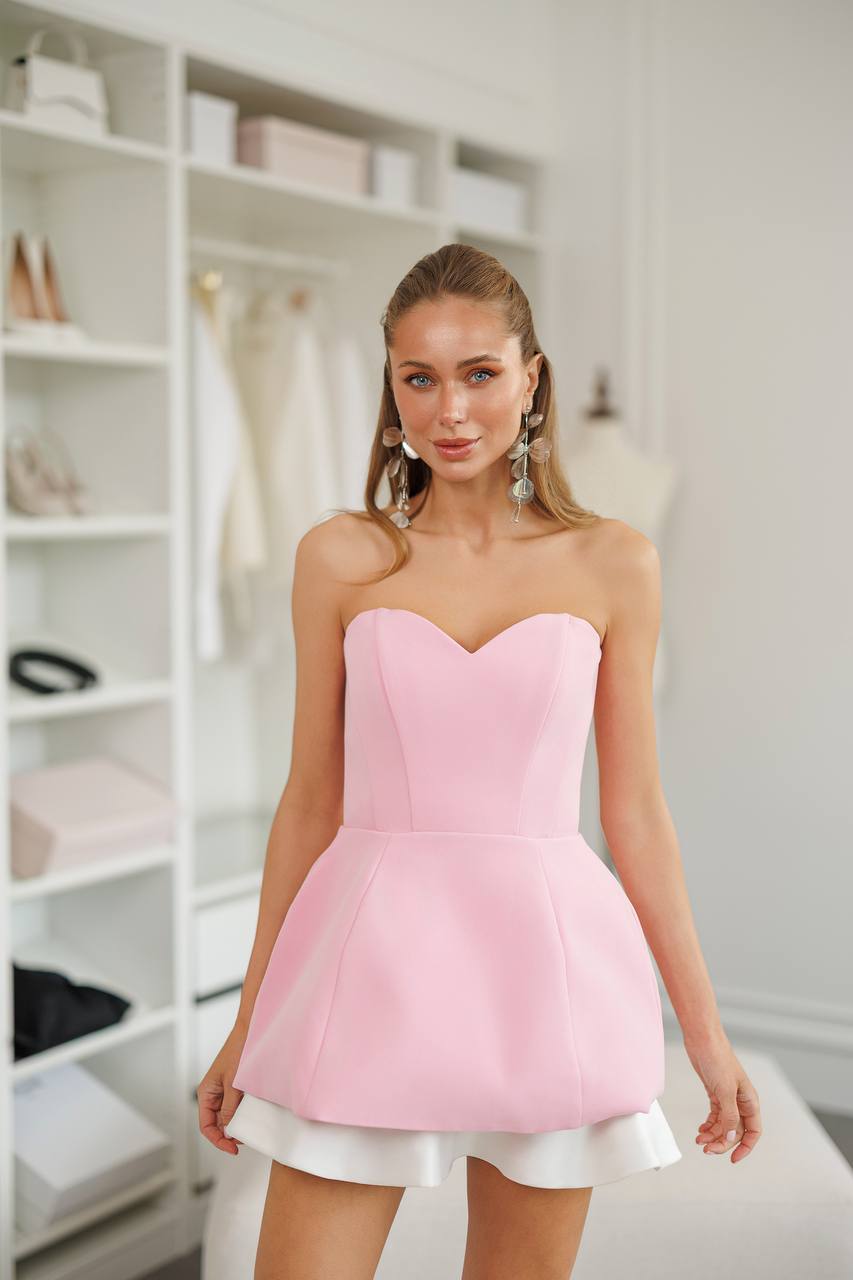 Woman wearing a pink strapless dress in a room with shelves.