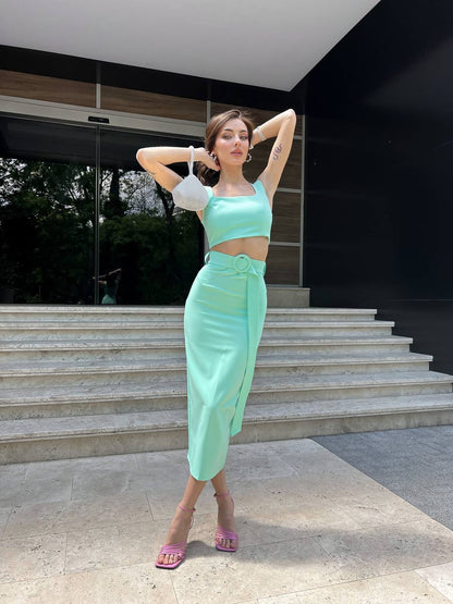 Woman in a light green outfit standing on steps outside a modern building.