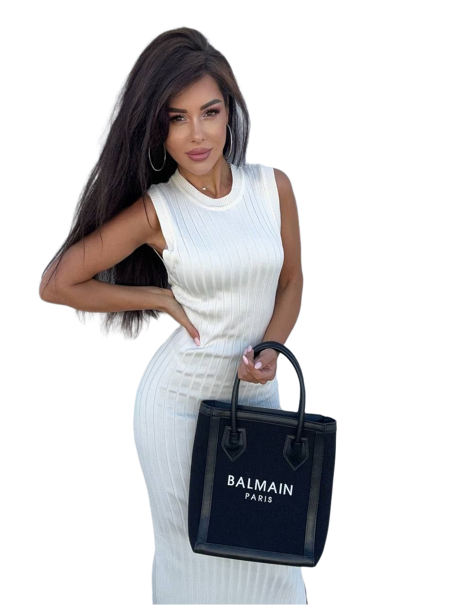 Woman holding a Balmain black handbag against a white background