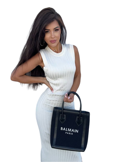 Woman holding a Balmain black handbag against a white background