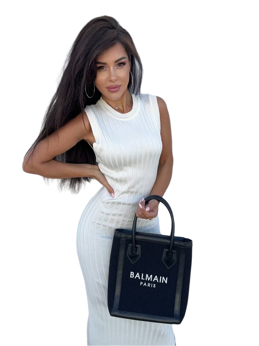 Woman holding a Balmain black handbag against a white background